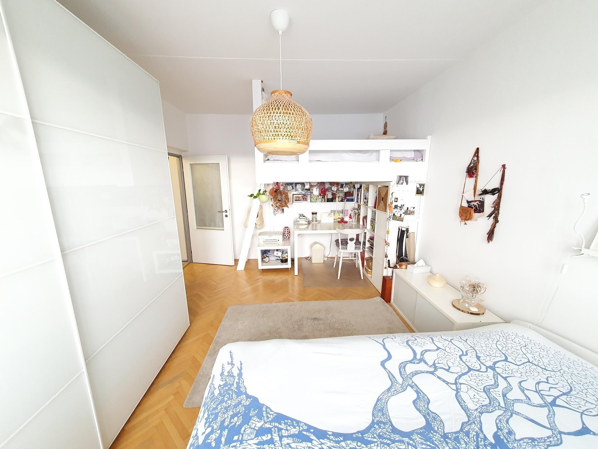 Prostorná ložnice s parketovou podlahou, světlým interiérem a vestavěnými skříněmi nabízí moderní a útulný prostor k bydlení.