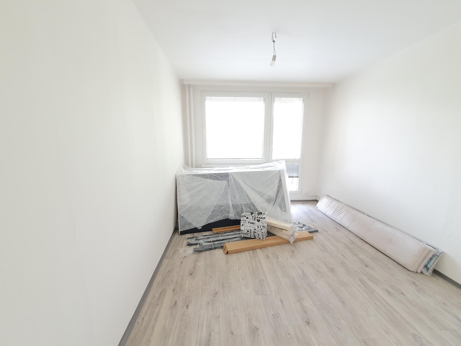 Světlý obývací pokoj s velkými okny, moderní vinylovou podlahou a přípravou na rekonstrukci interiéru.