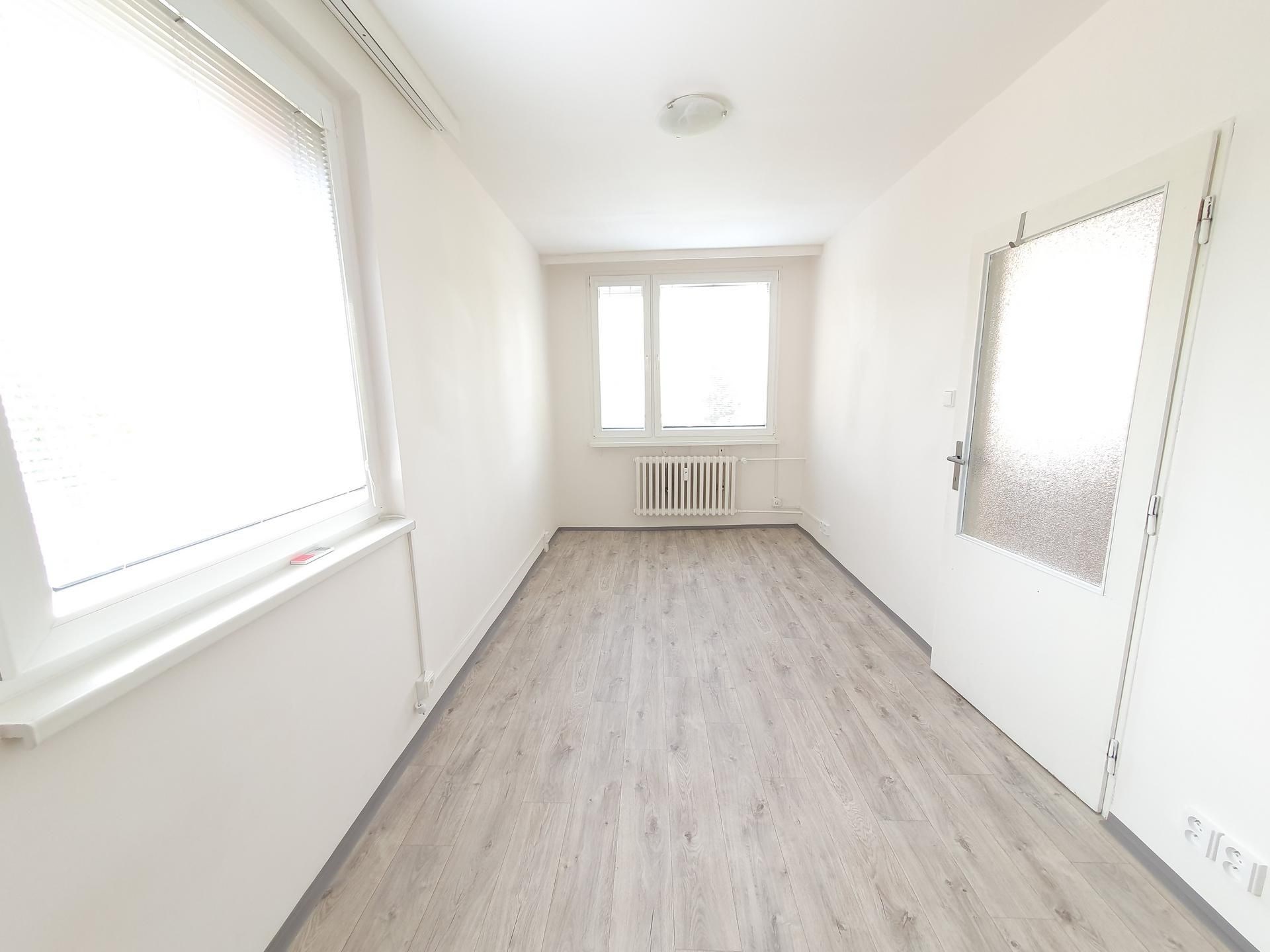 Chodba s laminátovou podlahou, světlý interiér s velkými okny a bílými zdmi, moderní design vhodný pro okamžité využití.