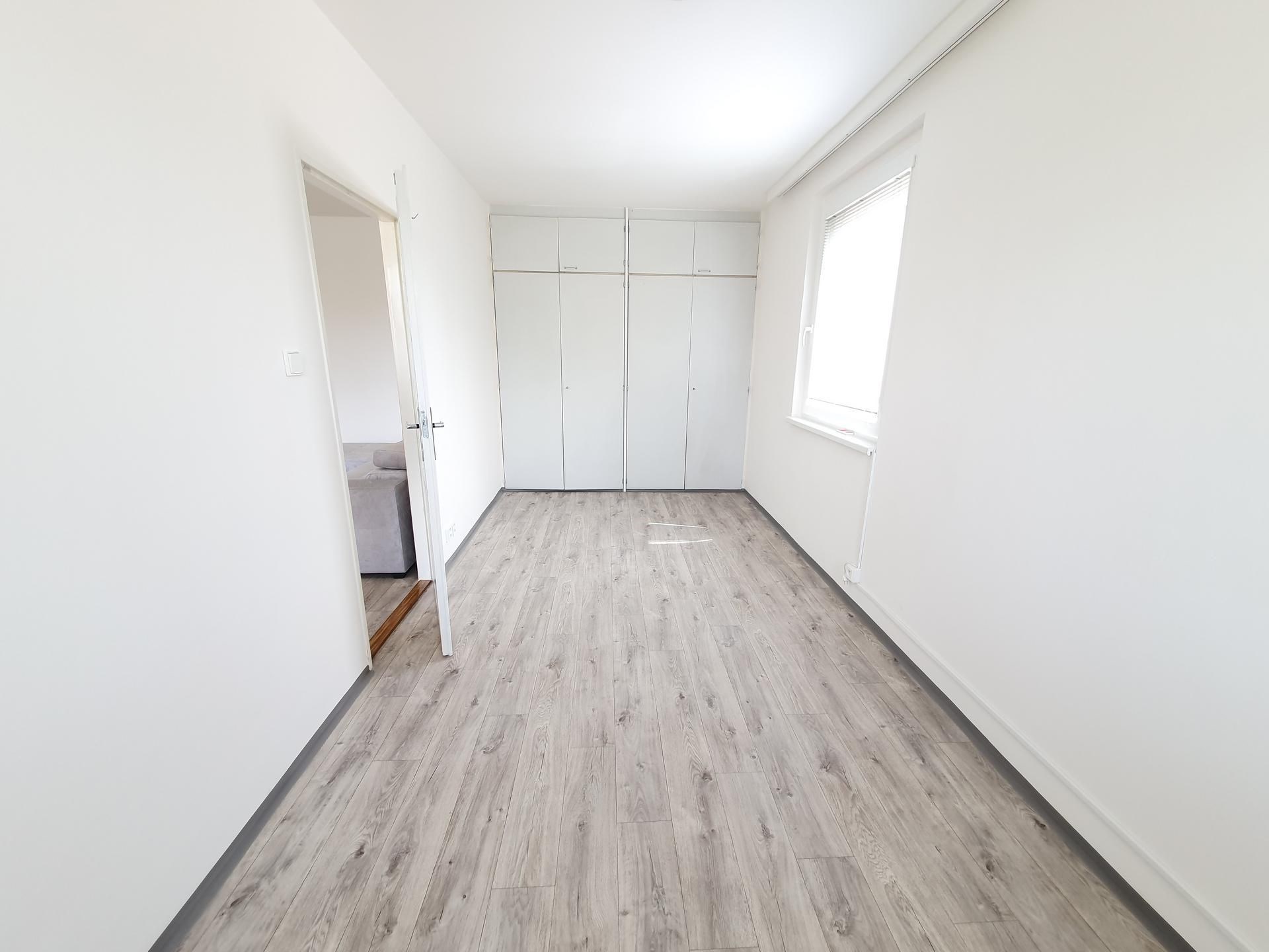 Prostorná ložnice s parketovou podlahou, vestavěné skříně, světlý interiér, moderní design, velká okna pro přirozené světlo